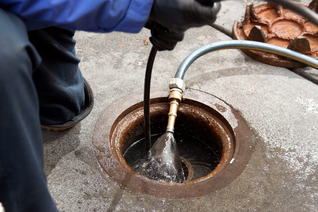 Plumber hydro jetting a sewer line through a manhole in Titusville
