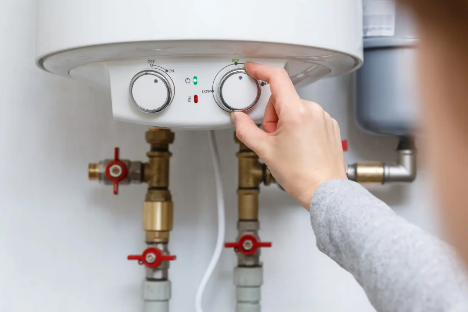Homeowner adjusting the temperature controls on a water heater in Titusville